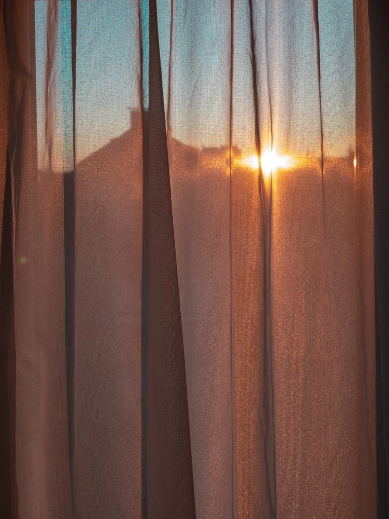 A quiet dawn view with a sheer curtain and a distant minaret